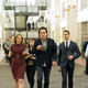 John Cusack (center holding glass) and Cory Michael Smith (right wearing tie) on Utopia.